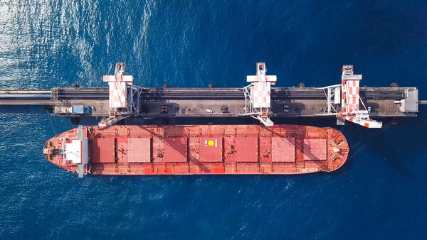 Red cargo ship from above, with hatch covers visible.